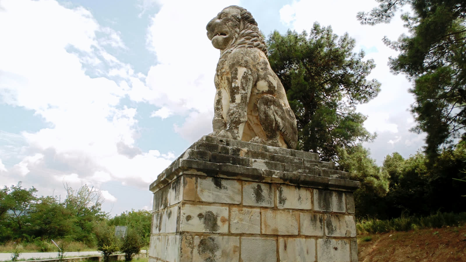 The marble Lion of Amphipolis on its plinth beside the road