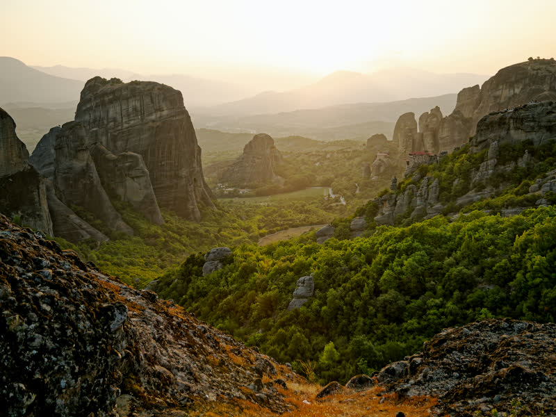 The rocks of Meteora at golden hour with a monastery on the skyline