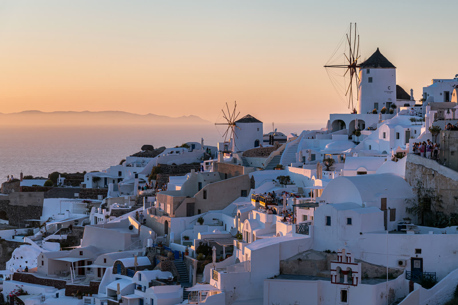 The windmills and white houses of Oia above the Santorini caldera at dusk