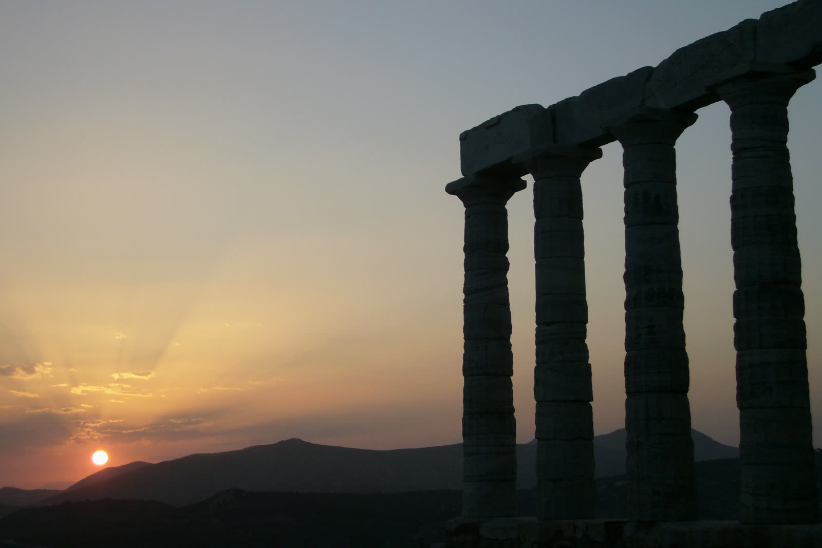 The Temple of Poseidon at Cape Sounion in silhouette above the Aegean at sunset
